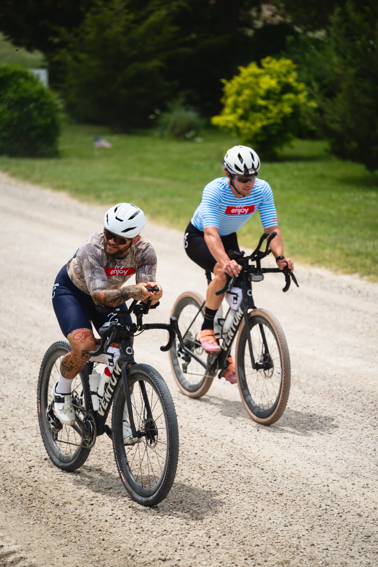 Two riders on a gravel road in Enjoy kit.
