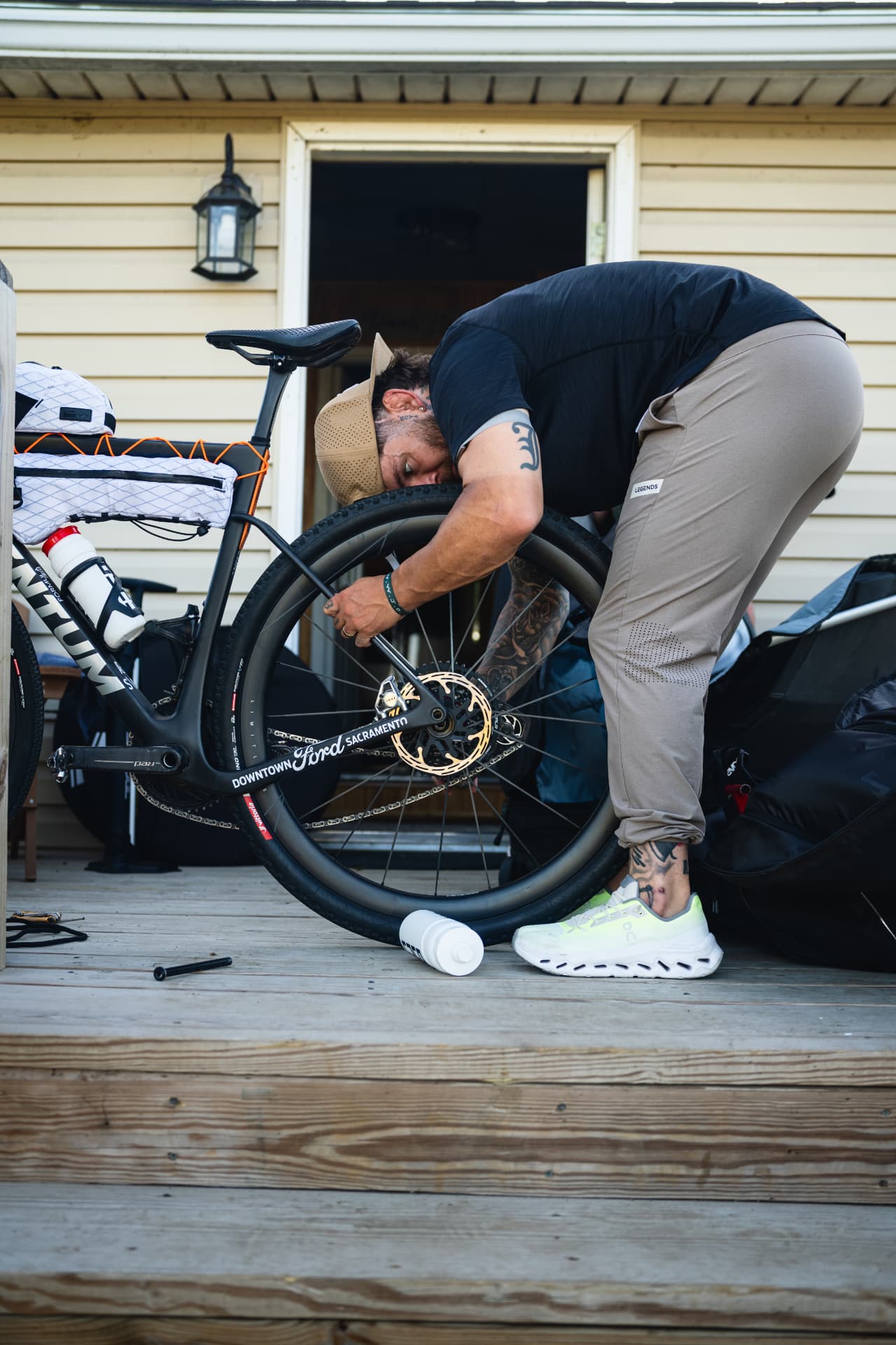 Rider working on a bike wheel on a wooden porch.
